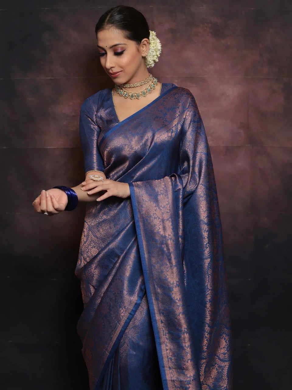 Woman wearing a blue saree with a dark background